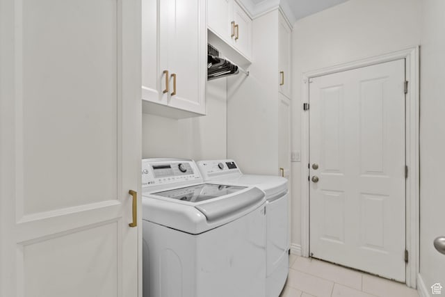 clothes washing area featuring separate washer and dryer, cabinet space, and light tile patterned floors