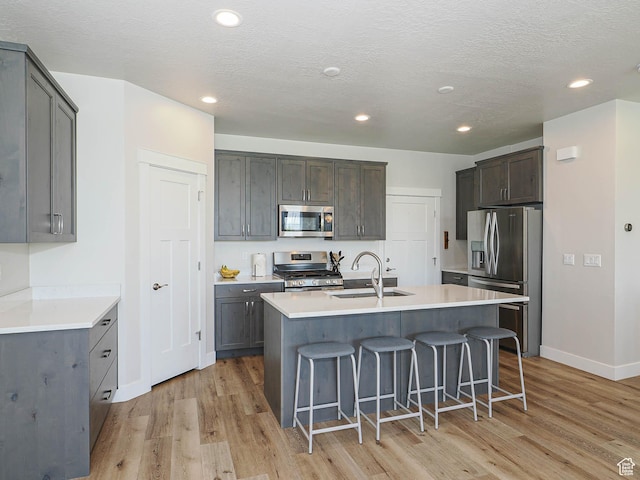 kitchen featuring a breakfast bar area, stainless steel appliances, a sink, and light wood finished floors