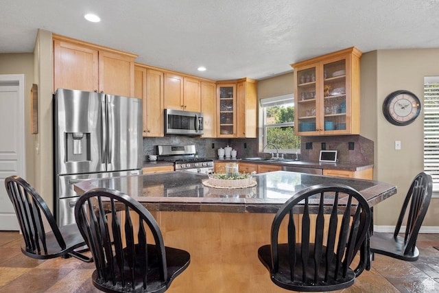 288 S Hillside Dr E, Elk Ridge, UT 84651 - kitchen with a kitchen bar, dark countertops, tasteful backsplash, a sink, and stainless steel appliances