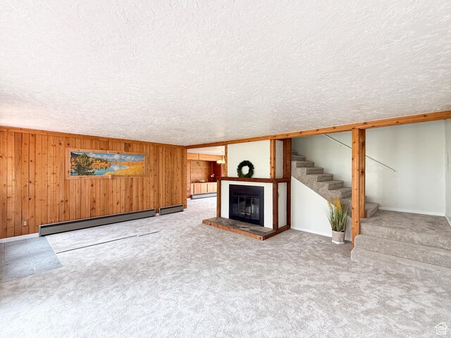 2160 N 730th St W, Garden City, UT 84028 - unfurnished living room featuring stairs, a glass covered fireplace, baseboard heating, wooden walls, and a textured ceiling