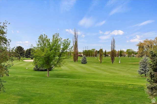 view of home's community featuring view of golf course and a yard