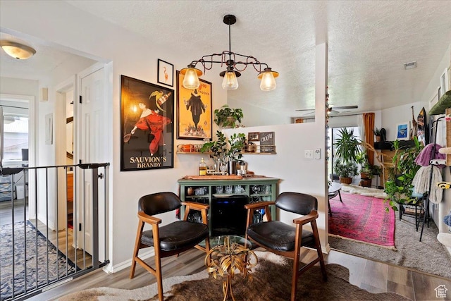 dining space featuring a textured ceiling, visible vents, and wood finished floors