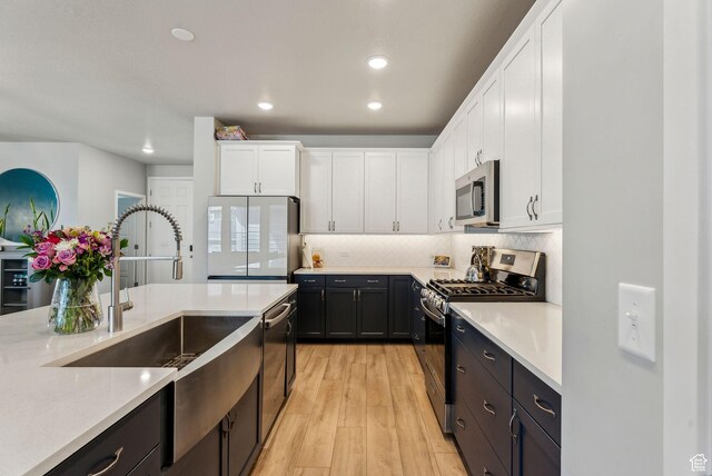 11619 S Silver Pond Dr W, South Jordan, UT 84009 - kitchen with appliances with stainless steel finishes, light countertops, light wood-style flooring, white cabinetry, and decorative backsplash