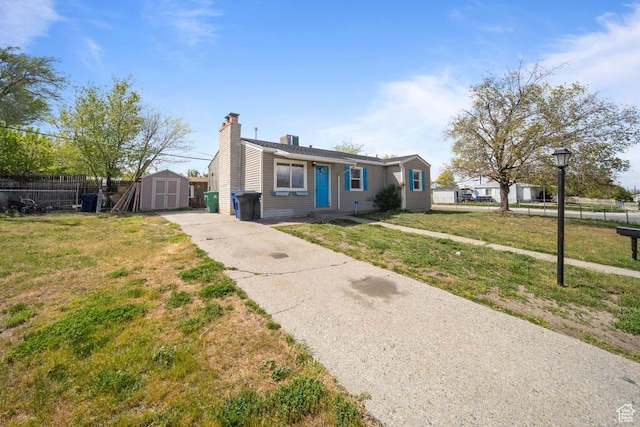 5390 S 4460 W, Kearns, UT 84118 - view of front facade featuring a front lawn, fence, a chimney, a storage unit, and an outbuilding