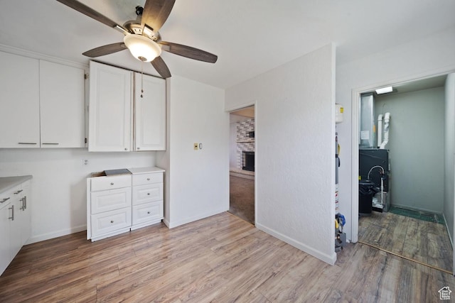 5390 S 4460 W, Kearns, UT 84118 - interior space with a fireplace, light countertops, a ceiling fan, white cabinetry, and light wood-type flooring