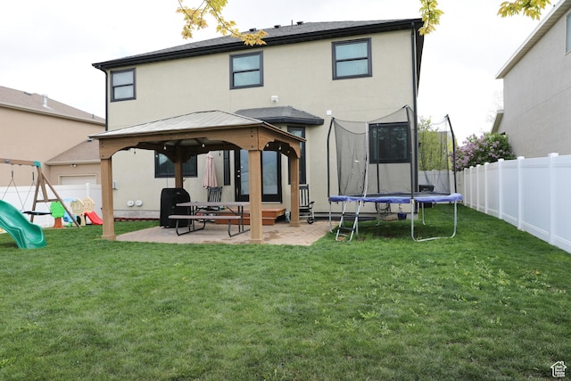 7044 W 8050 S, West Jordan, UT 84081 - back of house featuring a lawn, stucco siding, a patio area, a gazebo, and a trampoline