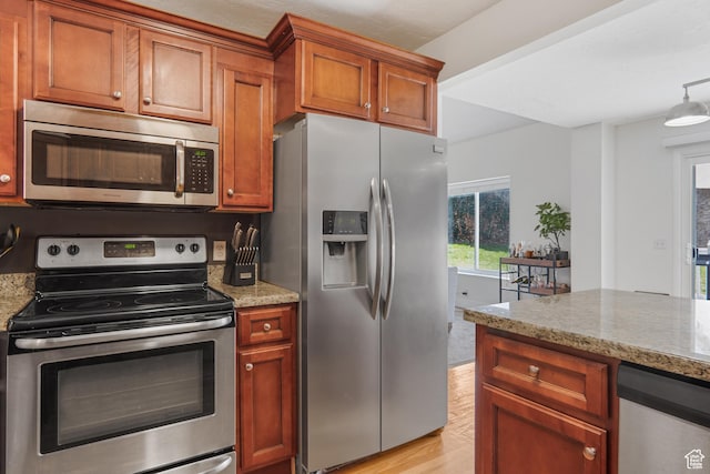 6888 S Hillside Village Cir, Salt Lake City, UT 84121 - kitchen featuring brown cabinetry, light wood finished floors, appliances with stainless steel finishes, and light stone countertops