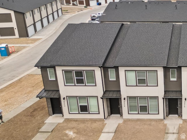 exterior space featuring a standing seam roof, a shingled roof, and stucco siding