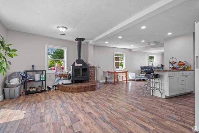 4207 W 5655 S, Salt Lake City, UT 84118 - living room featuring a wealth of natural light, a wood stove, a textured ceiling, and wood finished floors