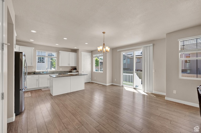 2770 S Sinbad Way W, Magna, UT 84044 - kitchen featuring dark countertops, a textured ceiling, a chandelier, freestanding refrigerator, and baseboards