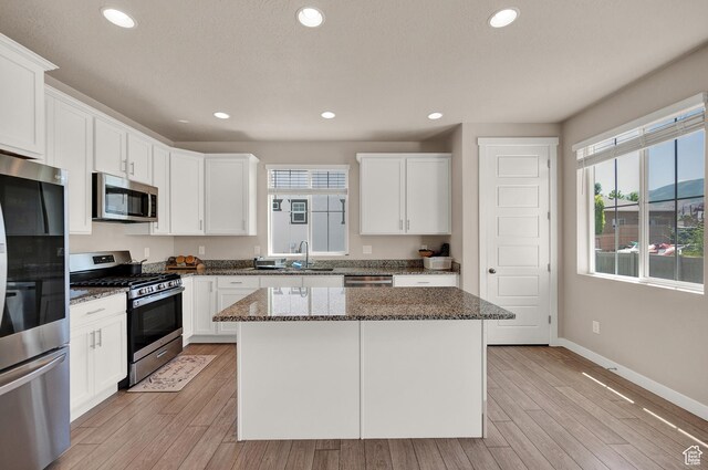 2770 S Sinbad Way W, Magna, UT 84044 - kitchen with light wood-style floors, a sink, dark stone countertops, and appliances with stainless steel finishes