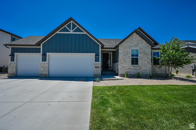 2770 S Sinbad Way W, Magna, UT 84044 - view of front of house featuring a front yard, stone siding, board and batten siding, an attached garage, and driveway