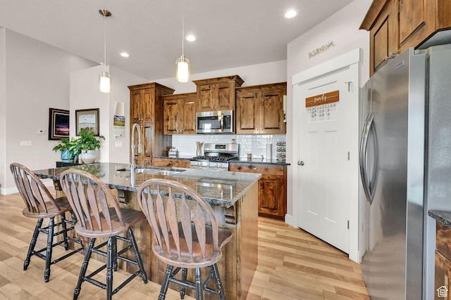 2515 W 3375 S, West Haven, UT 84401 - kitchen with appliances with stainless steel finishes, a sink, brown cabinetry, light wood-style flooring, and tasteful backsplash