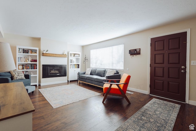 living room with baseboards, dark wood-style flooring, and a fireplace