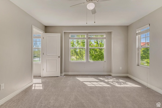 carpeted spare room featuring a ceiling fan and baseboards