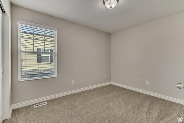carpeted empty room featuring visible vents and baseboards