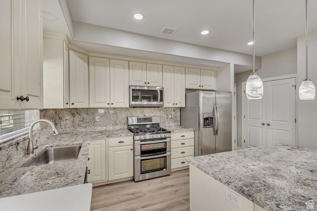 kitchen with a sink, appliances with stainless steel finishes, backsplash, and visible vents