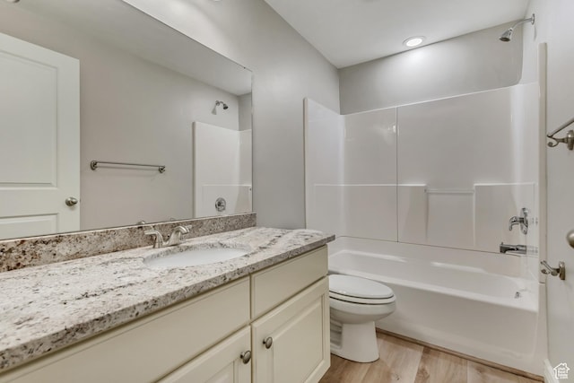 full bath featuring vanity, washtub / shower combination, wood finished floors, and toilet