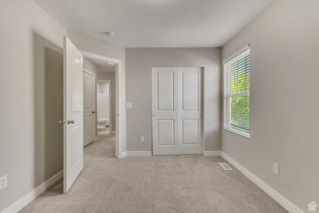 unfurnished bedroom featuring visible vents, baseboards, and light carpet