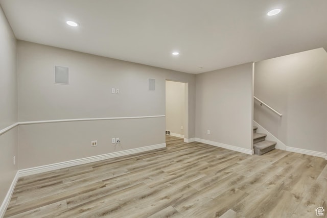 below grade area with baseboards, recessed lighting, light wood finished floors, and stairway