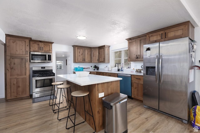 463 E Main St, Salina, UT 84654 - kitchen with a kitchen island, light wood-style floors, a kitchen bar, a textured ceiling, and stainless steel appliances