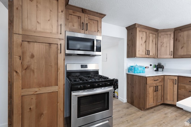 463 E Main St, Salina, UT 84654 - kitchen with light countertops, a textured ceiling, brown cabinets, light wood-style flooring, and stainless steel appliances