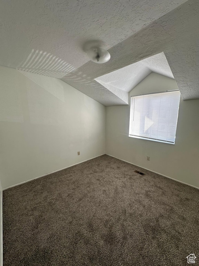 558 N Redwood Rd Unit 2-4, Salt Lake City, UT 84116 - bonus room featuring a textured ceiling, visible vents, vaulted ceiling, baseboards, and carpet flooring