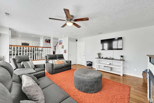 267 W 1600 N, Layton, UT 84041 - living room featuring light wood finished floors, a fireplace, a textured ceiling, a ceiling fan, and baseboards