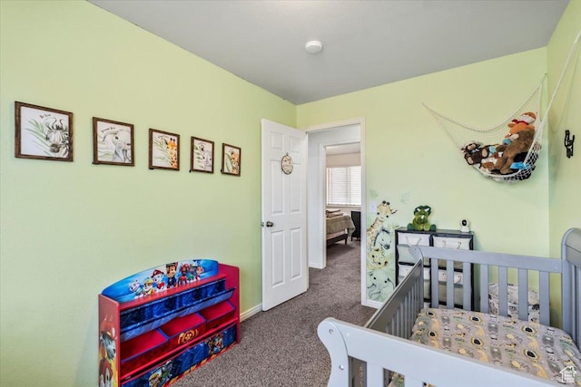 bedroom featuring a nursery area, baseboards, and carpet