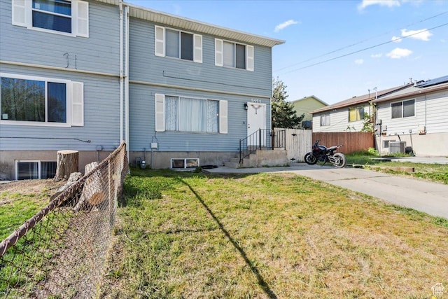 view of front of house featuring fence, cooling unit, and a front lawn