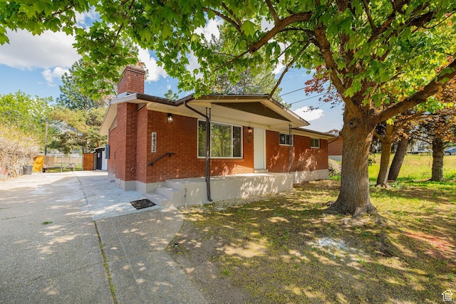 4432 Orchard Ave, South Ogden, UT 84403 - view of side of property with brick siding, driveway, and a chimney