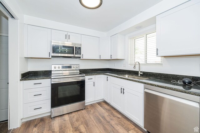 4432 Orchard Ave, South Ogden, UT 84403 - kitchen featuring dark wood-style floors, white cabinets, a sink, dark stone countertops, and appliances with stainless steel finishes