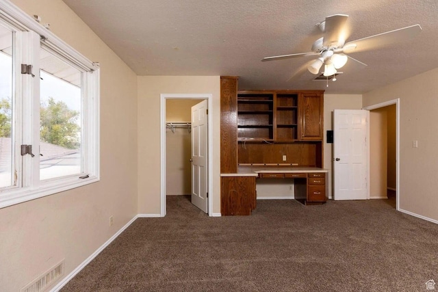 623 E 160 S, St George, UT 84770 - unfurnished bedroom with a walk in closet, visible vents, built in desk, baseboards, and dark carpet