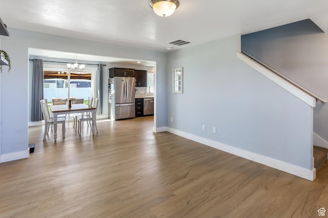 1150 W 200 S, Logan, UT 84321 - unfurnished living room featuring a chandelier, baseboards, visible vents, and light wood finished floors