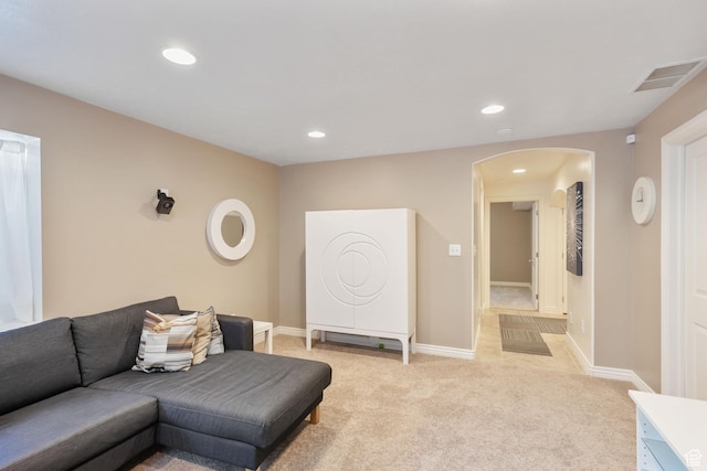 living room with visible vents, baseboards, light colored carpet, recessed lighting, and arched walkways