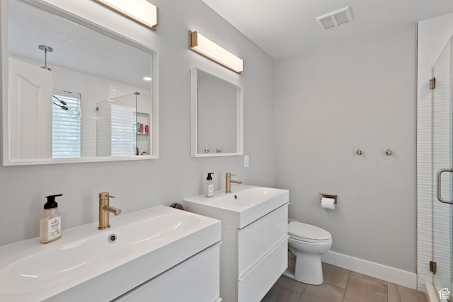 bathroom featuring visible vents, toilet, two vanities, a sink, and a stall shower