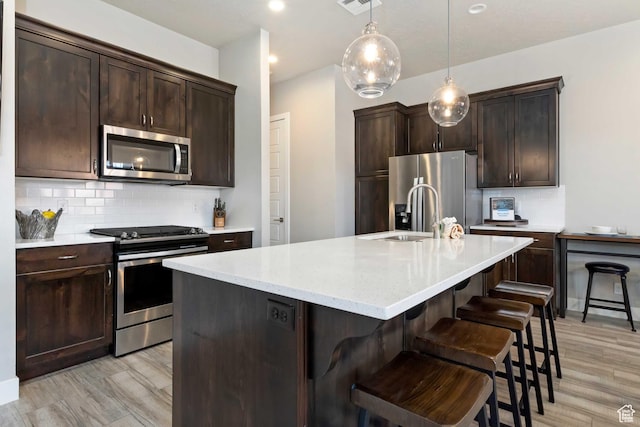 2600 Ocotillo Way Unit 31, Santa Clara, UT 84765 - kitchen featuring appliances with stainless steel finishes, a sink, dark brown cabinetry, tasteful backsplash, and light wood-style flooring