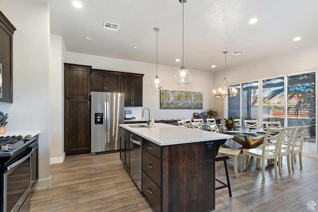2600 Ocotillo Way Unit 31, Santa Clara, UT 84765 - kitchen featuring stainless steel appliances, a sink, light wood finished floors, a breakfast bar area, and dark brown cabinets