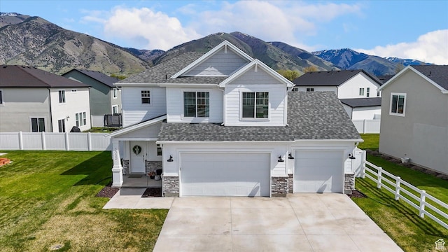 3030 S 400 W, Nibley, UT 84321 - view of front of house with a front yard, stone siding, a shingled roof, concrete driveway, and a mountain view
