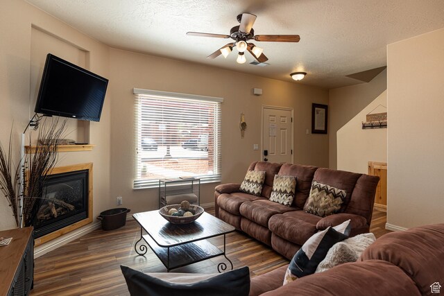 300 E 300 N Unit L5, Kanab, UT 84741 - living area featuring wood finished floors, a glass covered fireplace, ceiling fan, baseboards, and a textured ceiling