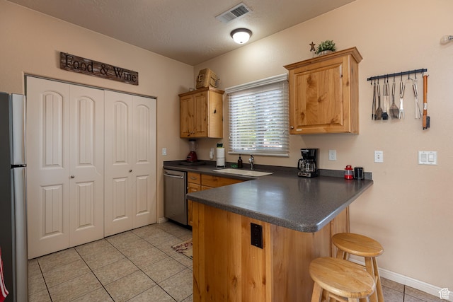 300 E 300 N Unit L5, Kanab, UT 84741 - kitchen featuring appliances with stainless steel finishes, a sink, dark countertops, light tile patterned flooring, and a peninsula