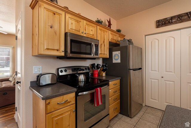 300 E 300 N Unit L5, Kanab, UT 84741 - kitchen with stainless steel appliances, a textured ceiling, dark countertops, and light tile patterned floors
