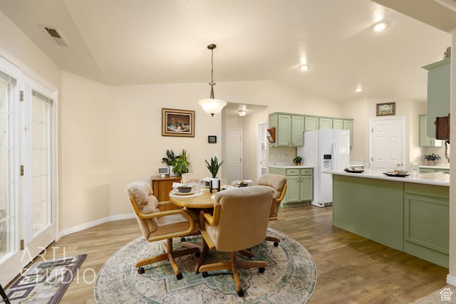 dining area with baseboards, lofted ceiling, light wood-style flooring, and visible vents