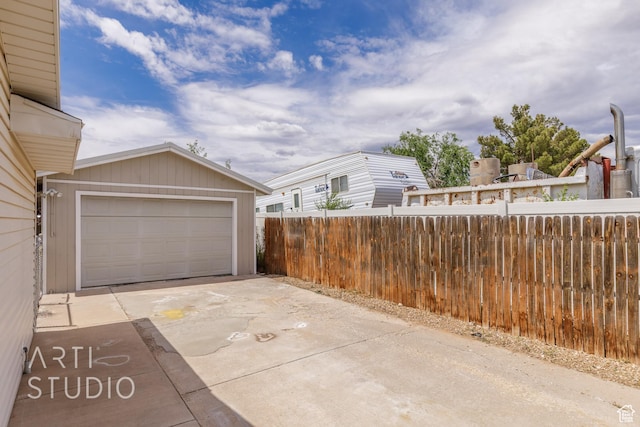 garage featuring fence and driveway