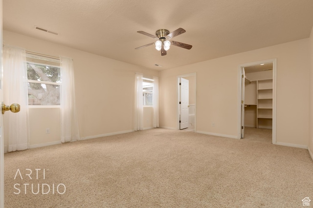 unfurnished bedroom featuring visible vents, baseboards, connected bathroom, a spacious closet, and carpet flooring