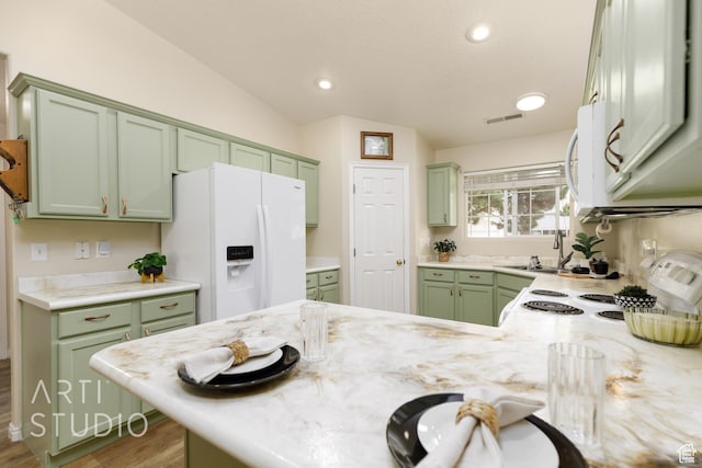 kitchen featuring green cabinetry, a sink, white appliances, wood finished floors, and visible vents
