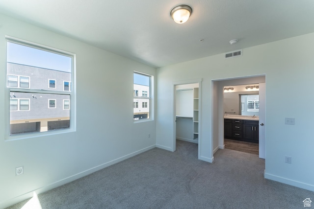 unfurnished bedroom featuring visible vents, baseboards, a closet, a spacious closet, and carpet flooring