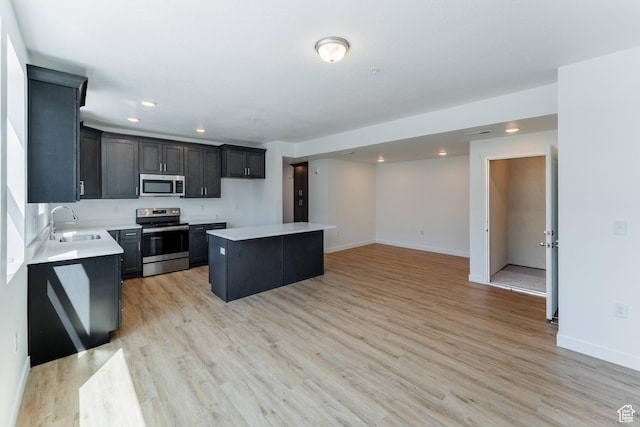 kitchen featuring a kitchen island, appliances with stainless steel finishes, a sink, light countertops, and recessed lighting