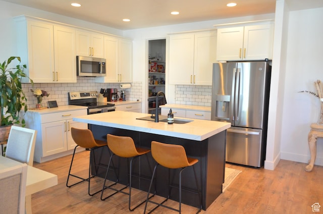kitchen with stainless steel appliances, a breakfast bar, a sink, and light wood-style flooring