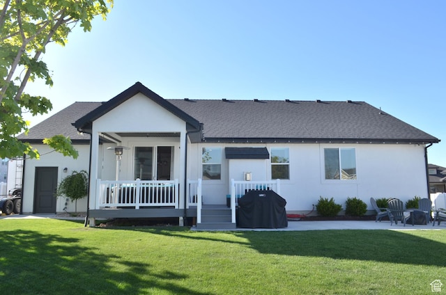 rear view of property with a lawn, a patio, stucco siding, and roof with shingles